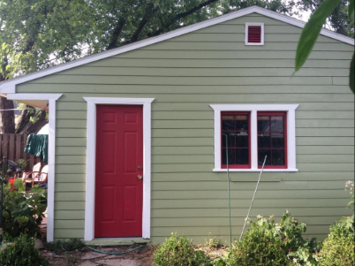 Whole exterior garage painted green siding, white trim, and red door and red inlay around windows